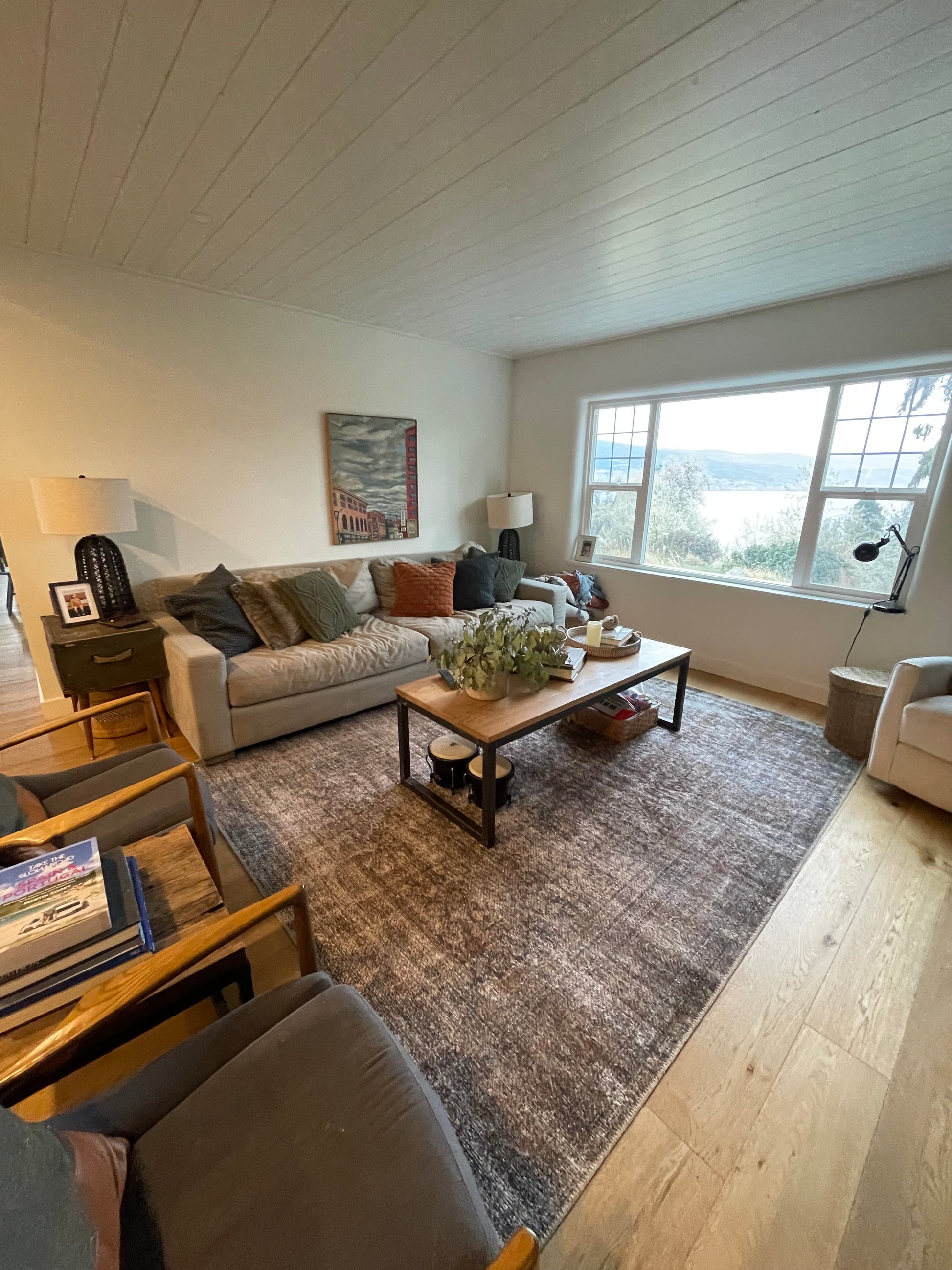 A picture of a living room with hardwood floors and an area rug with a coffee tabel, couch and two chairs all cleaned to perfection with a view out the newly cleaned window.